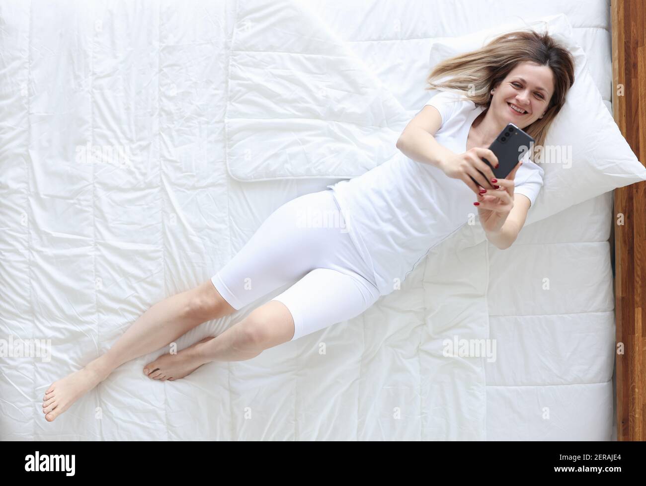 Femme en pyjama blanc couché au lit et prenant le selfie vue de dessus  Photo Stock - Alamy
