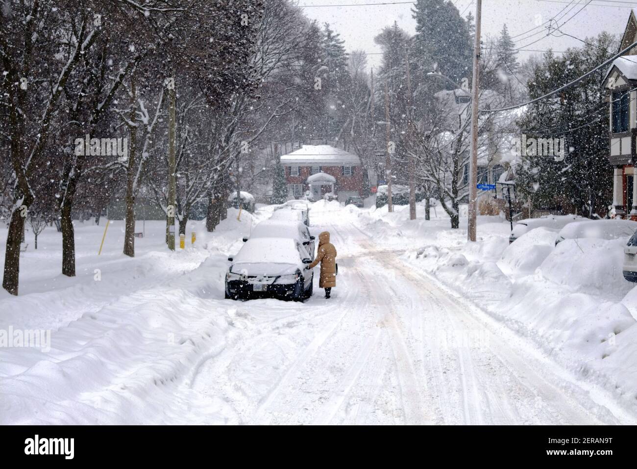 Personne sous un manteau d'hiver beige entrant dans sa voiture enneigée lors d'une tempête de neige à Ottawa, Ontario, Canada. Banque D'Images