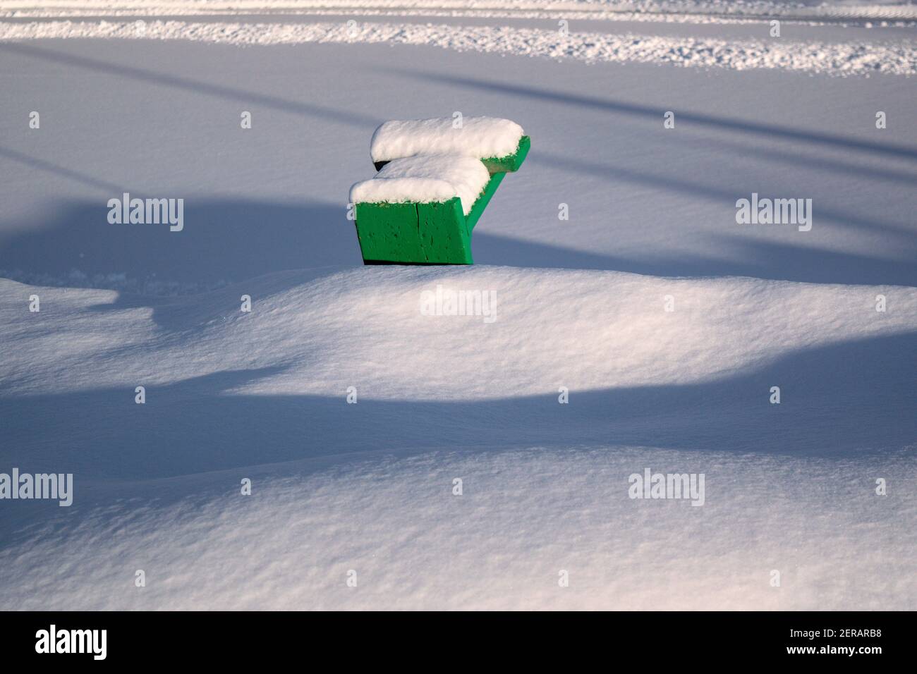 De longues ombres, (haut d'un) banc vert et beaucoup de neige fraîche. Le Bal de neige prend fin en raison de la hausse des températures. Ottawa, Ontario, Canada. Banque D'Images