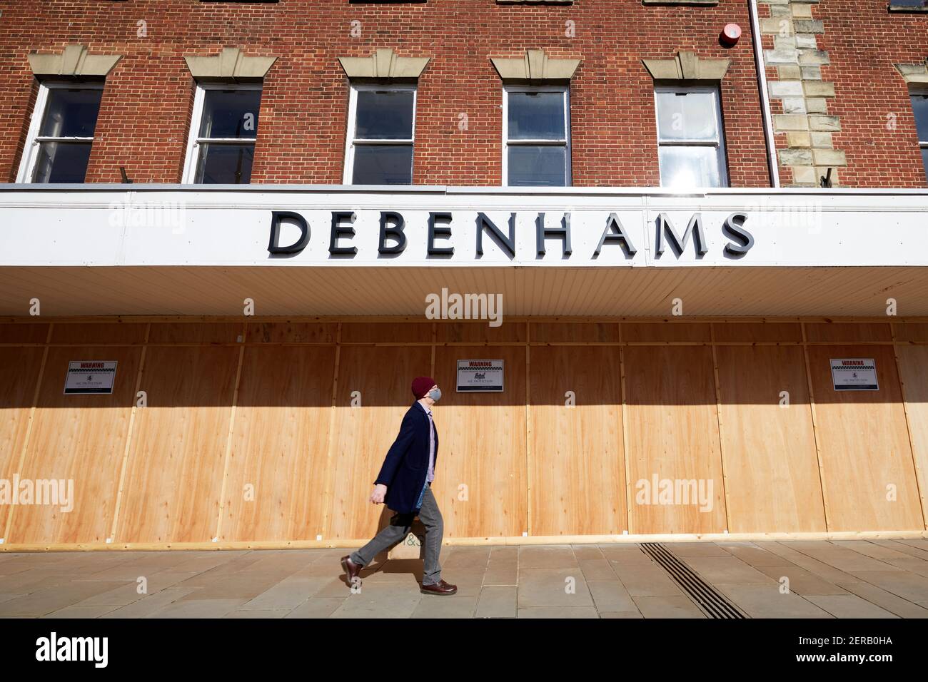 Salisbury, Royaume-Uni - 28 février 2021 : une promenade piétonne à l'abri du visage, le long de l'ancien magasin de Debenhams à bord, près d'un an après sa fermeture. La boutique a été fermée pendant le premier confinement du coronavirus au printemps 2020 et n'a pas pu rouvrir. Banque D'Images