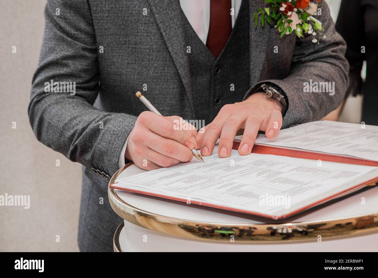 Les mains du marié sont signées avec un stylo dans le document sur la confirmation du mariage en gros plan. Banque D'Images