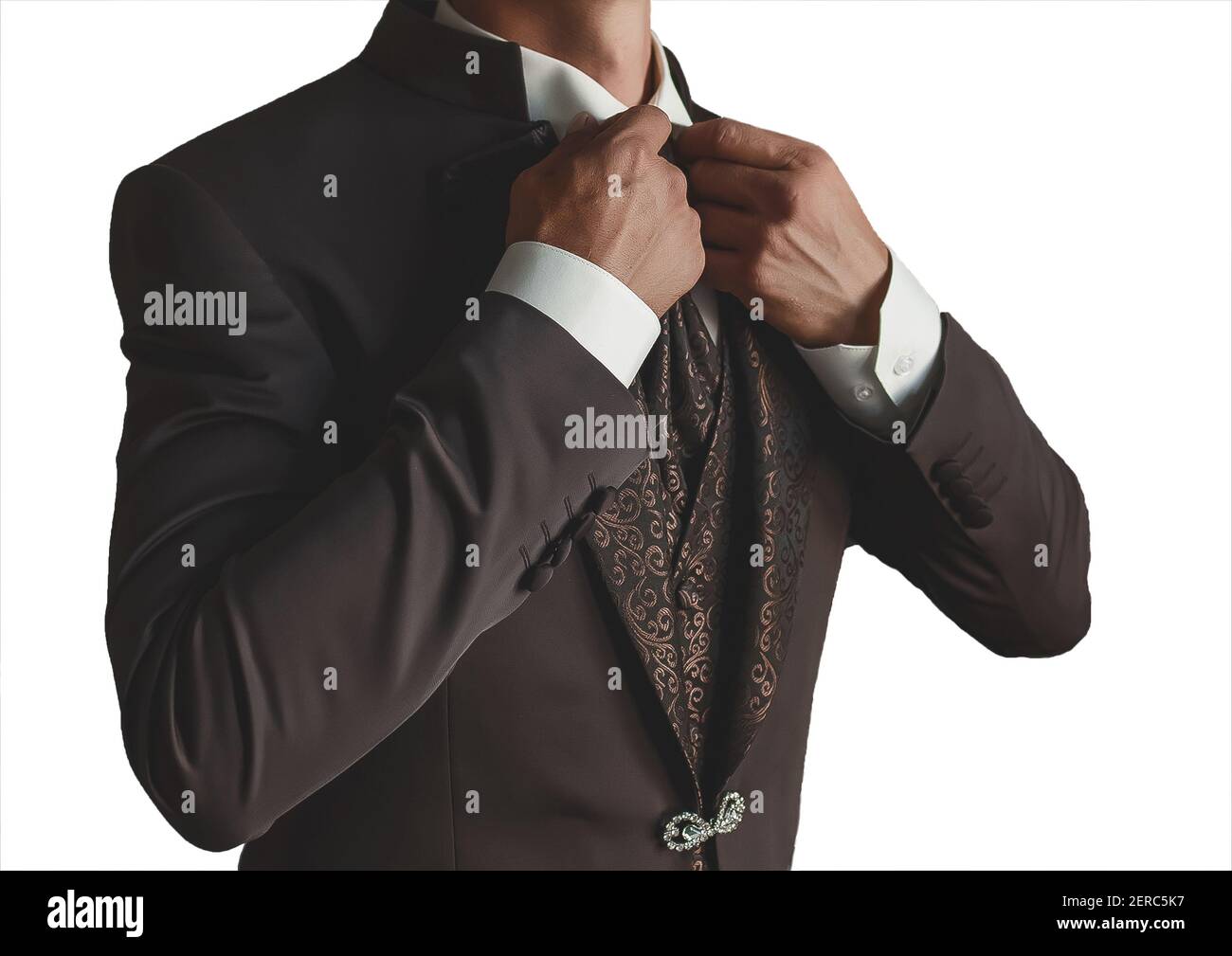Un homme dans une chemise blanche et marron élégant costume avec des motifs redresse le col avec ses mains sur un fond blanc, isolé. Banque D'Images