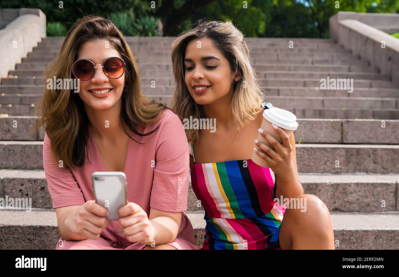 Deux amis utilisant un téléphone mobile à l'extérieur. Banque D'Images