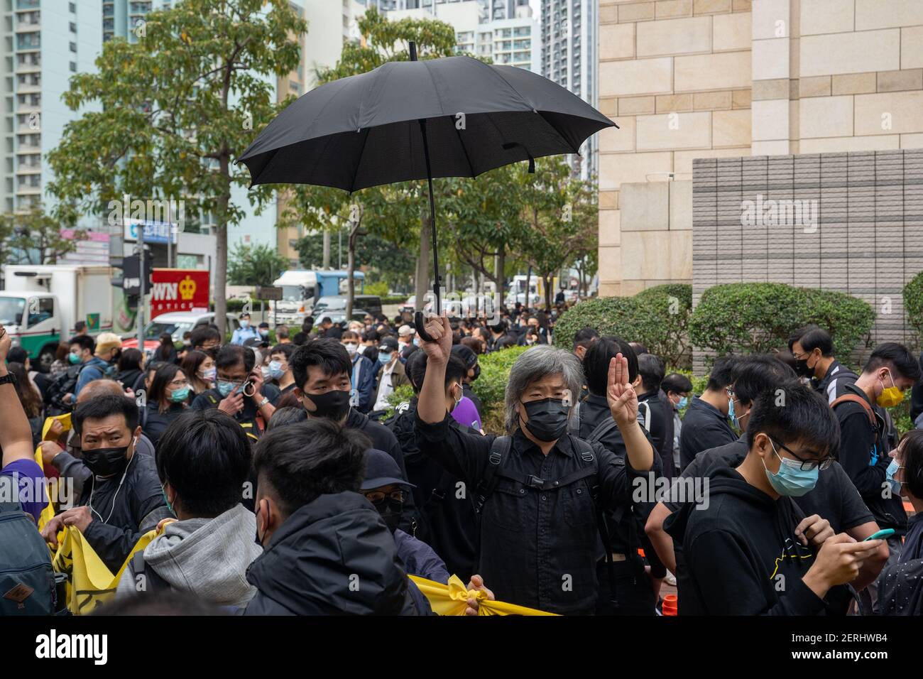 Un militant pro-démocratie tient un parapluie noir tout en faisant les  trois doigts saluer en soutien aux activistes arrêtés devant la cour de  Kowloon.47 les activistes pro-démocratie accusés de conspiration pour  renverser