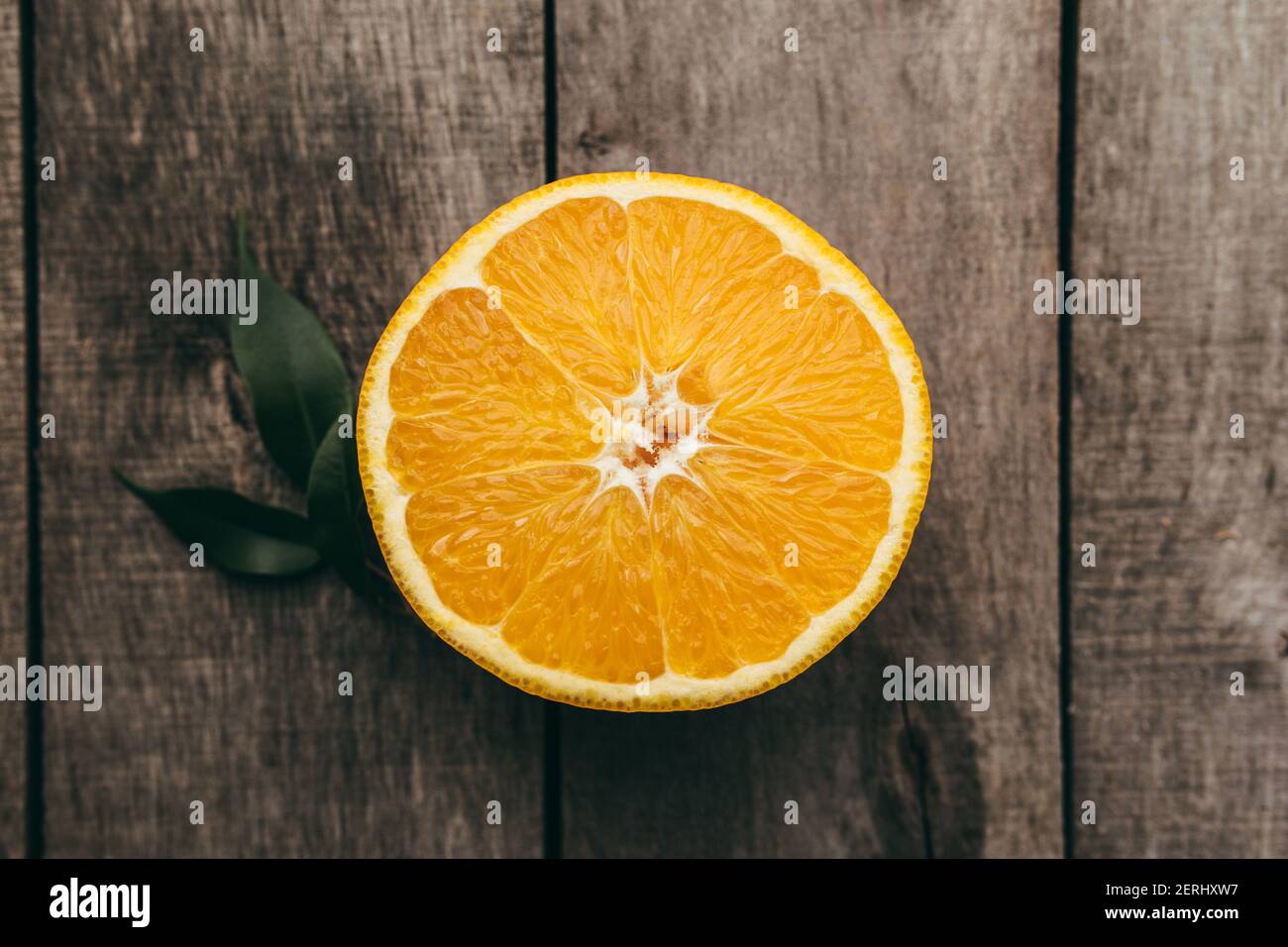 Tranches de fruits orange sur fond de bois gris. Pulpe et feuilles vertes. Photo de haute qualité Banque D'Images