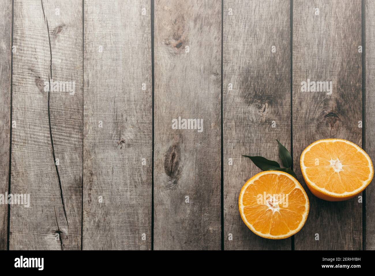Tranches de fruits orange sur fond de bois gris. Pulpe et feuilles vertes. Photo de haute qualité Banque D'Images