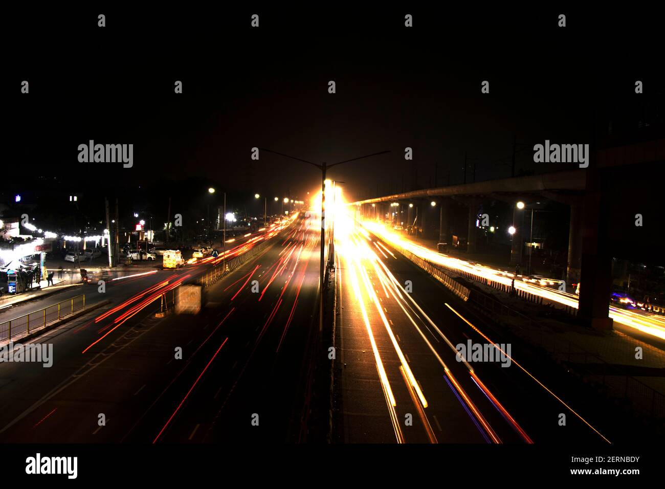 Vitesse la circulation des pistes lumineuses sur l'autoroute, longue exposition, fond urbain et ciel sombre Banque D'Images