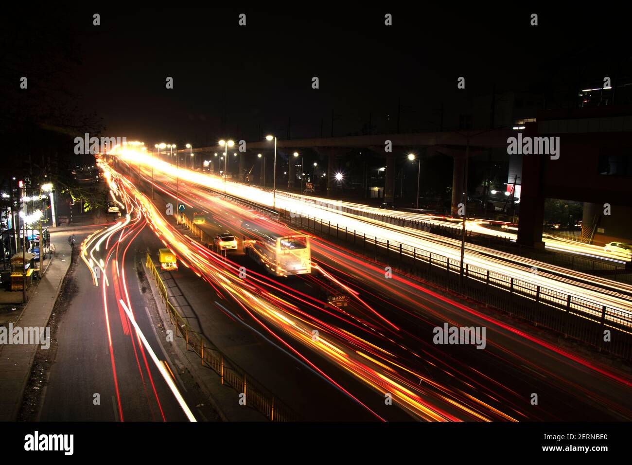 Vitesse la circulation des pistes lumineuses sur l'autoroute, longue exposition, fond urbain et ciel sombre Banque D'Images