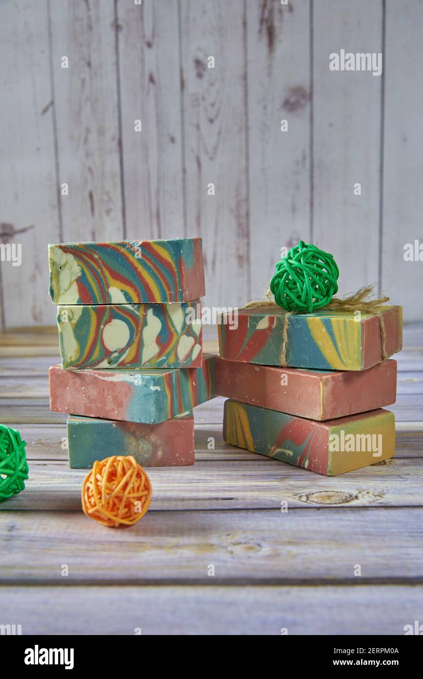 Plusieurs morceaux de savon biologique artisanal multicolore et diverses décorations sur fond gris clair. Banque D'Images