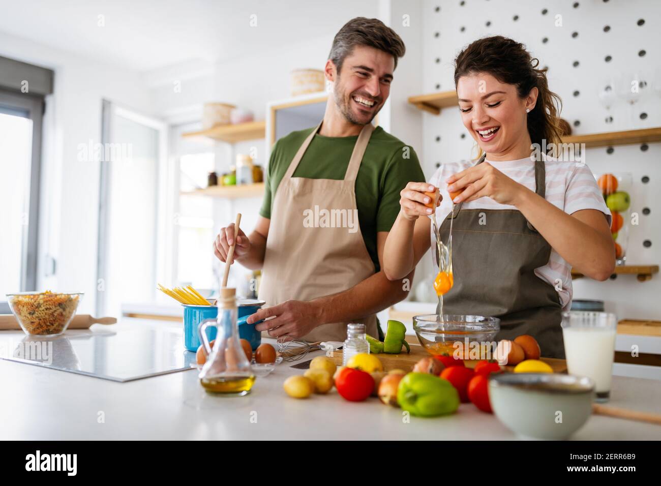 Un jeune couple heureux s'amuse dans une cuisine moderne tout en se préparant produits frais Banque D'Images