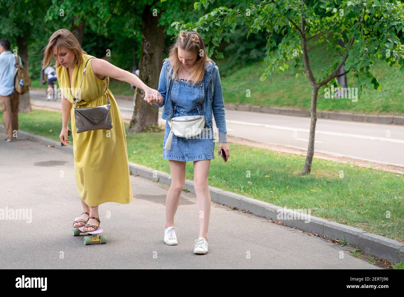 mère et fille passent du temps ensemble. fille enseigne à maman à skate sur un skateboard. Banque D'Images