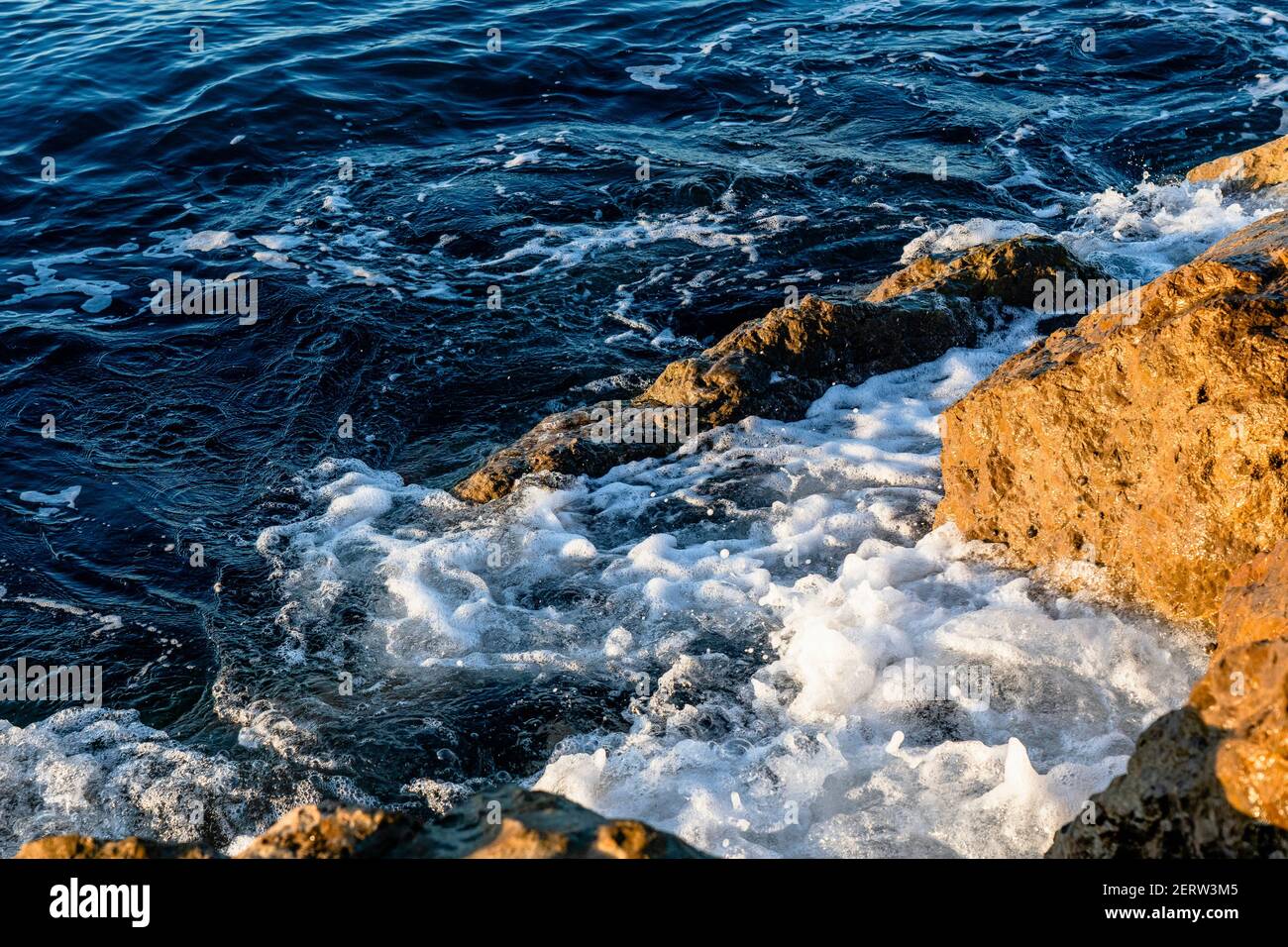 Vagues écrasant sur les rochers de la plage le matin. Lever du soleil sur la mer ondulée avec des rochers Banque D'Images