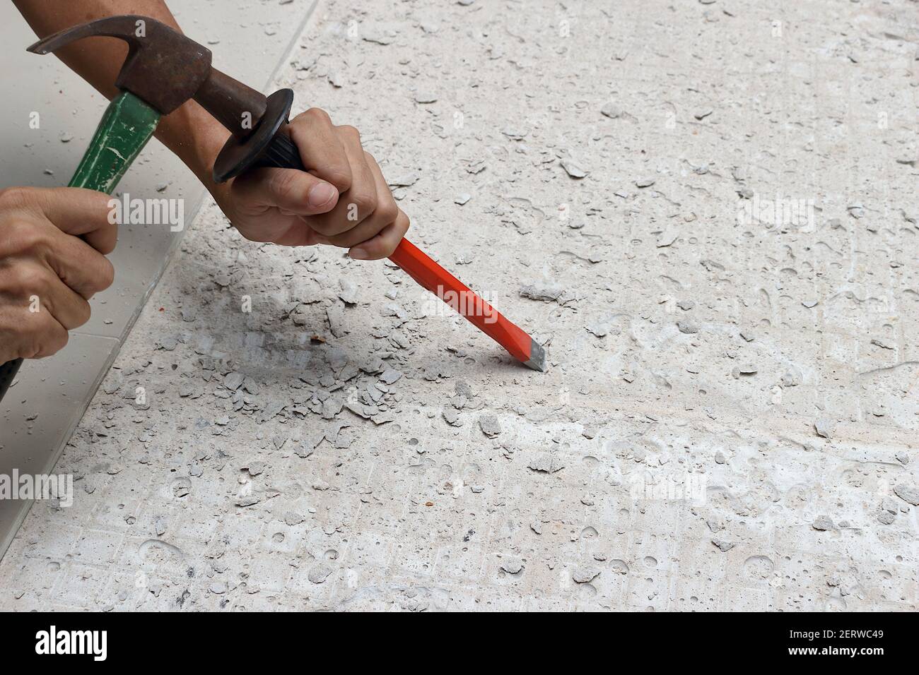 Un mécanicien martelait un burin dans le sol pour préparer la zone pour le nouveau carrelage. Banque D'Images