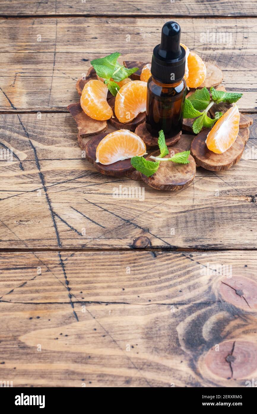 Huile de mandarine aromatique dans une bulle sombre, huile cosmétique de mandarine sur fond de bois, espace de copie Banque D'Images Huile de mandarine aromatique dans une bulle sombre, huile cosmétique de mandarine sur fond de bois, espace de copie Banque D'Images