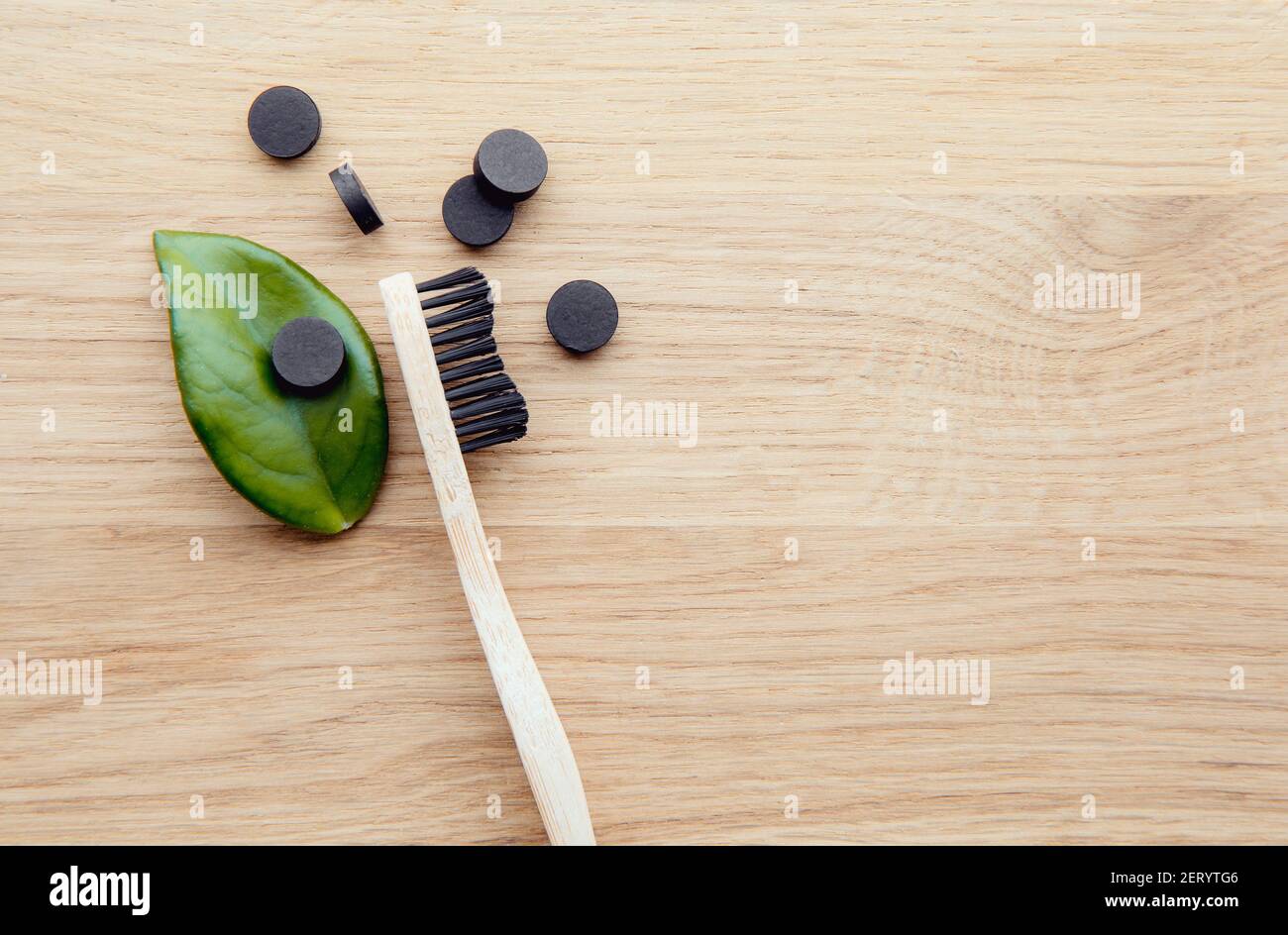 Comprimés de dentifrice au charbon actif noir. Concept de soins dentaires. Ingrédients naturels, vue du dessus de la brosse à dents en bambou avec des comprimés de dentifrice noirs. Banque D'Images