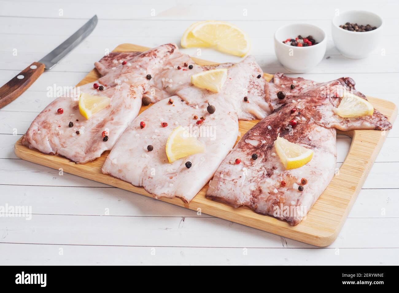 Carcasse de calmar crue avec épices et citron prêt à cuire sur un espace de copie en bois de planche à découper. Vue de dessus Banque D'Images Carcasse de calmar crue avec épices et citron prêt à cuire sur un espace de copie en bois de planche à découper. Vue de dessus Banque D'Images