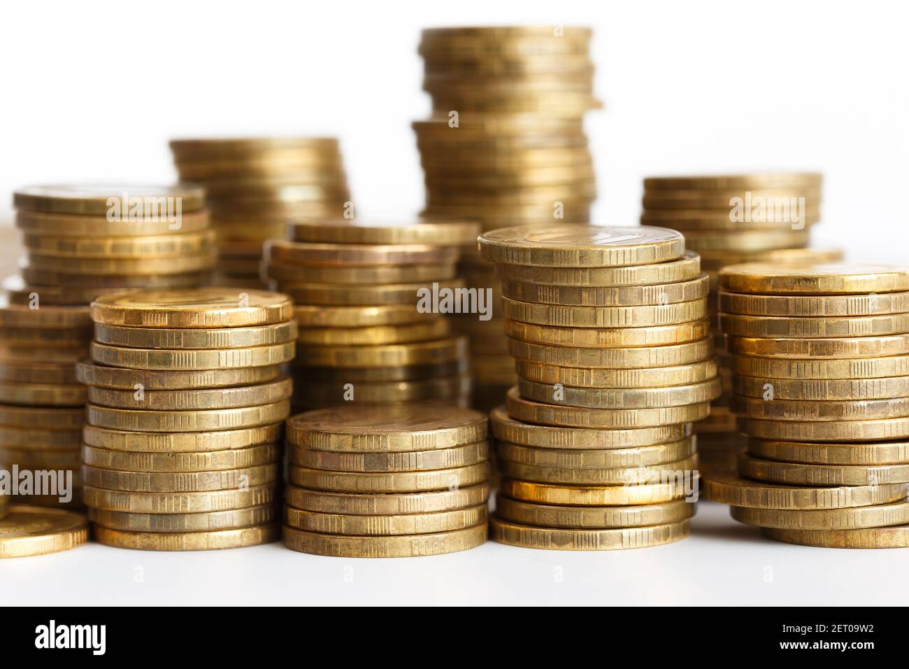 Pièces de monnaie dorées empilées en piles sur fond blanc Banque D'Images