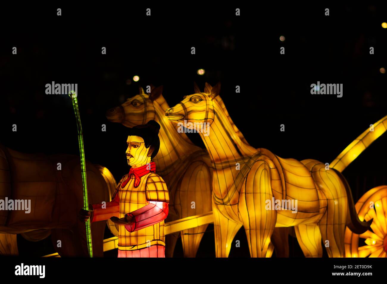 Festival des lanternes chinoises au parc de Limanski. Un homme avec une écharpe rouge, tenant un bâton de bambou, se tient à côté d'une calèche tirée par des chevaux. Banque D'Images