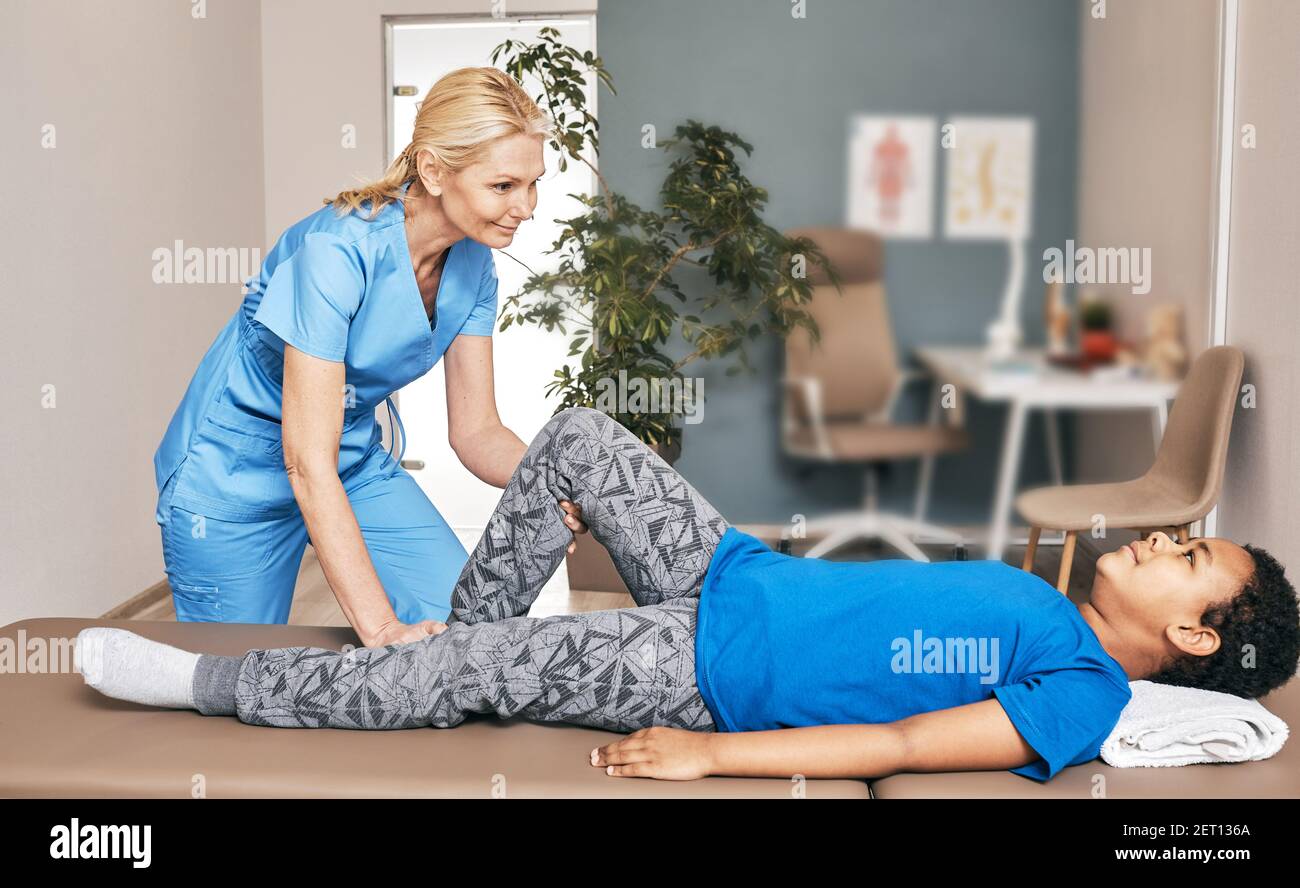 Chiropraticien faire un exercice pour traiter le genou d'un enfant. Douleurs au genou, blessures au genou. Bureau du traumatologue Banque D'Images