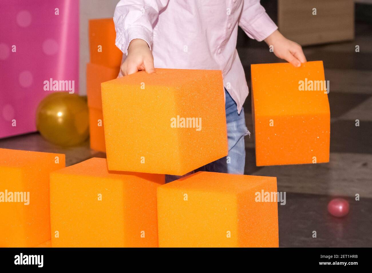 de grands blocs de paralon orange dans le centre pour enfants. l'enfant construit un mur à partir de cubes doux. Banque D'Images