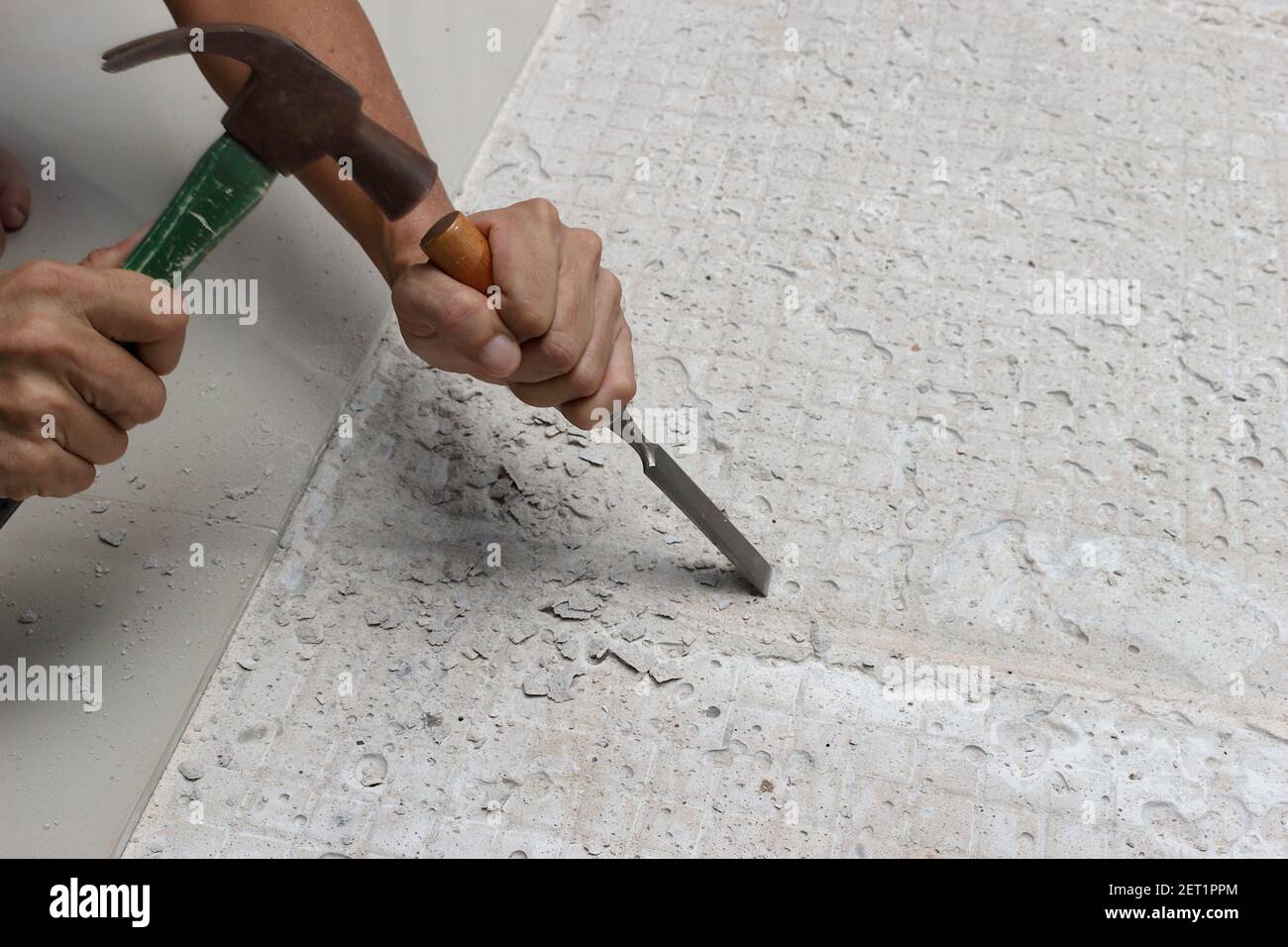 Un mécanicien martelait un burin dans le sol pour préparer la zone pour le nouveau carrelage. Banque D'Images