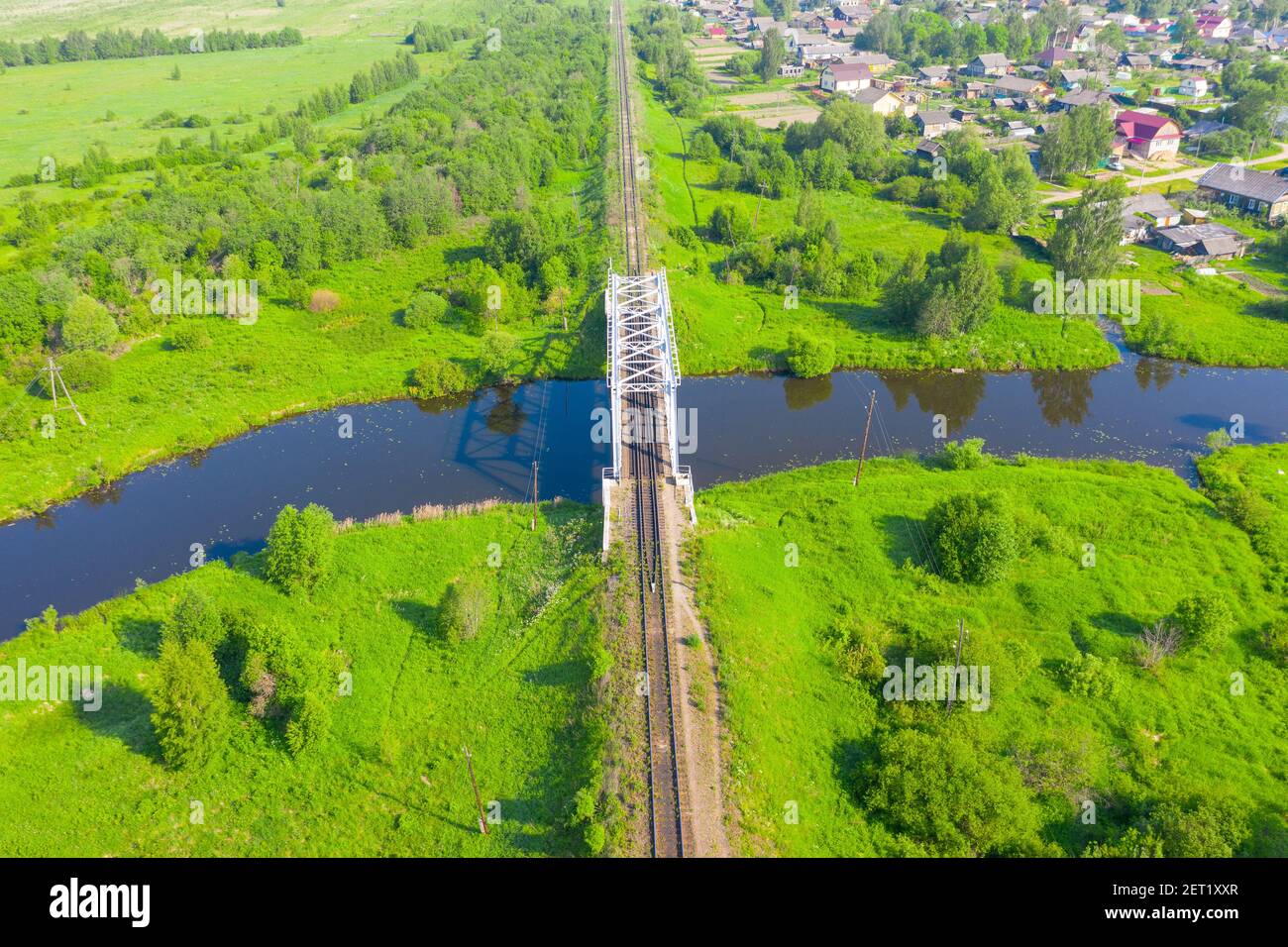 Pont de chemin de fer au milieu de prairies verdoyantes sur une petite rivière dans la campagne, vue aérienne Banque D'Images