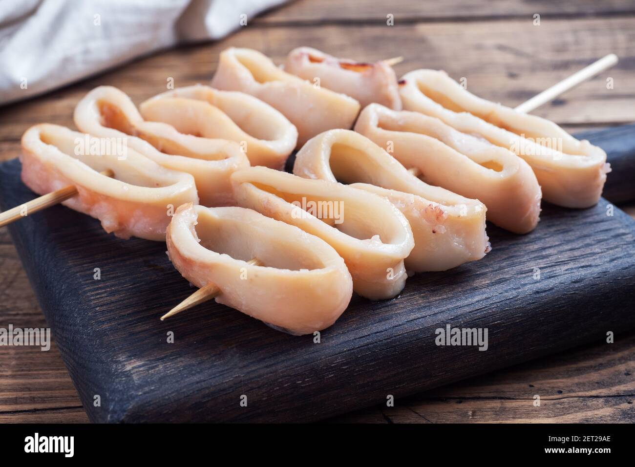 Rondelles de calmar frites sur une brochette avec sauce tomate et citron. Arrière-plan en bois foncé. Vue de dessus Banque D'Images Rondelles de calmar frites sur une brochette avec sauce tomate et citron. Arrière-plan en bois foncé. Vue de dessus Banque D'Images