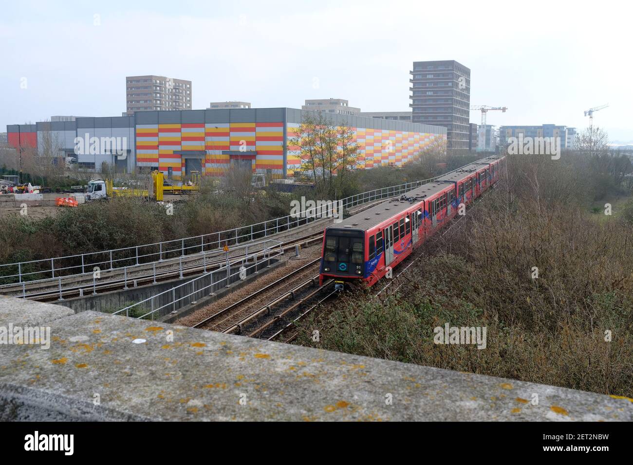 BECKTON, LONDRES - 1ER MARS 2021 : un train DLR qui part de la gare de Gallions Reach, avec le bâtiment BDM Logistics en arrière-plan Banque D'Images