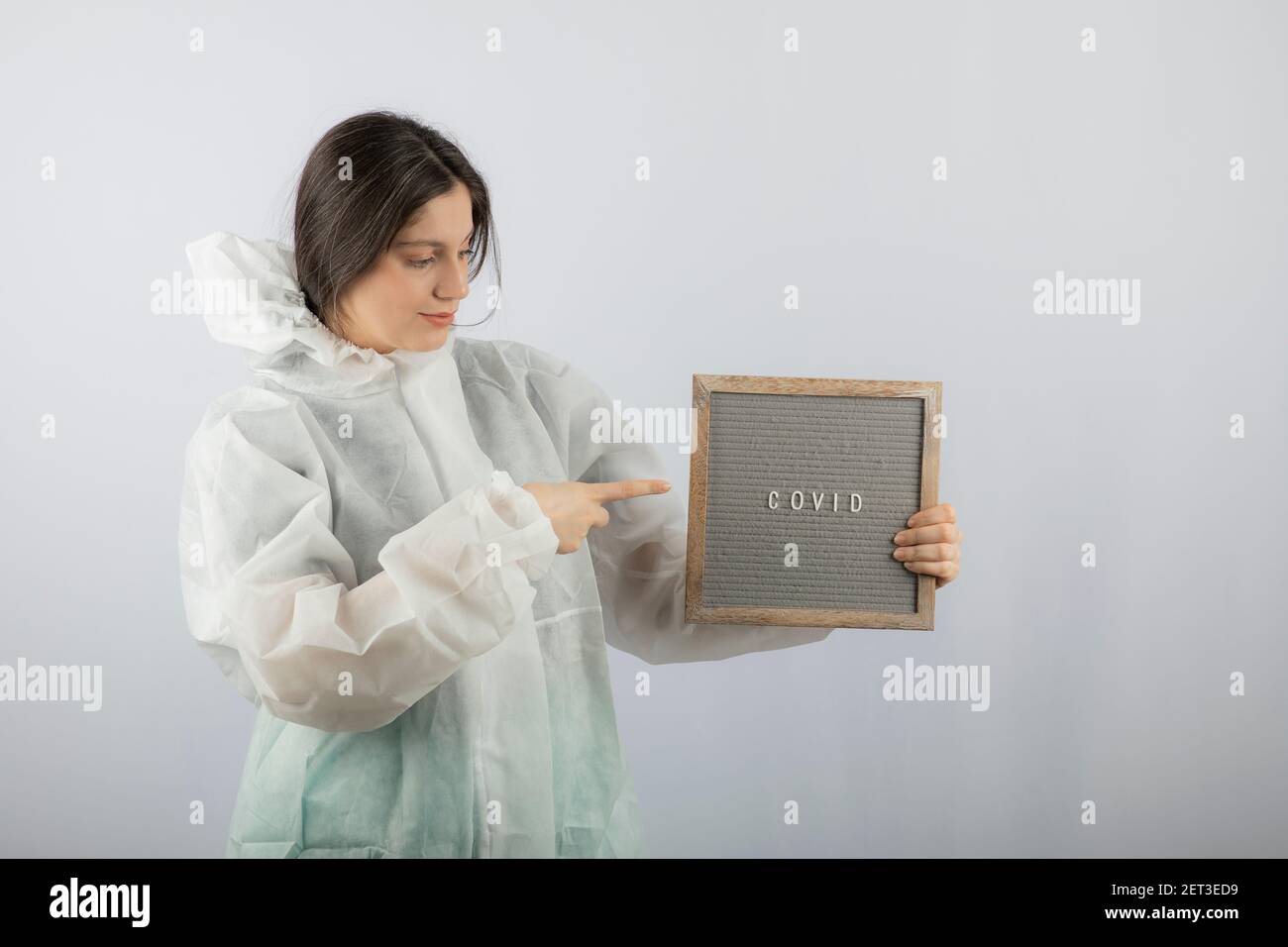 Photo d'un modèle de jeune fille en blouse de laboratoire défensive pointant vers un cadre Banque D'Images