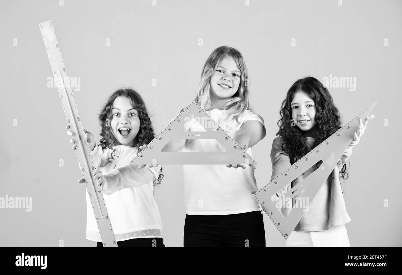 Etudier dur pour de bonnes notes. Sujet favori de géométrie. Éducation et concept scolaire. Les élèves de l'école apprennent la géométrie. Mathématiques. Sciences exactes. Trois filles avec triangle et règle. Retour à l'école. Banque D'Images