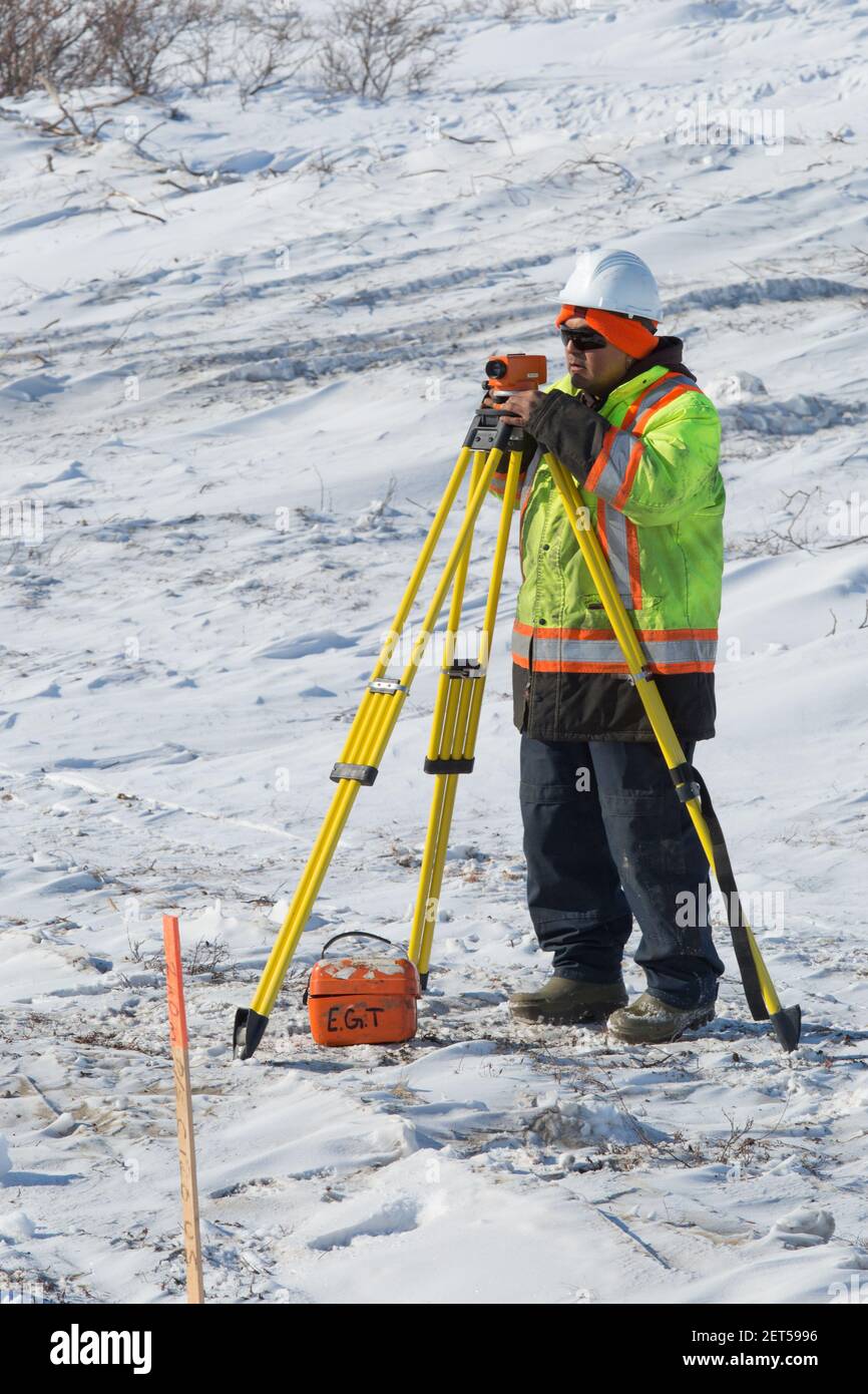 Travailleur masculin arpentage de la route Inuvik-Tuktoyaktuk, construction hivernale, Territoires du Nord-Ouest, Arctique canadien, avril 2014. Banque D'Images
