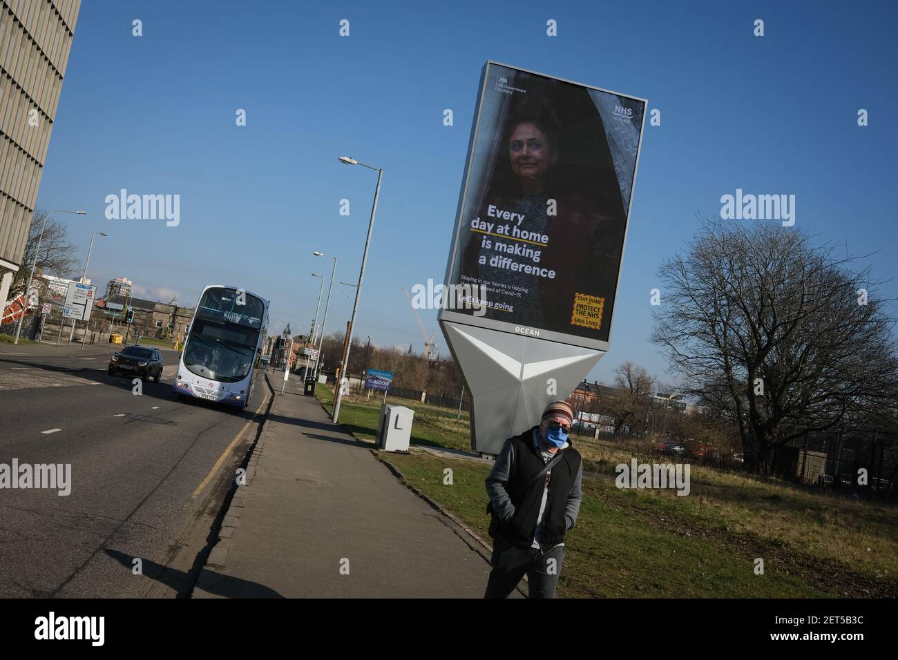 Glasgow, Royaume-Uni, le 1er mars 2021. Un piéton passe devant un panneau d'affichage électronique à grande échelle qui indique les directives de sécurité pour la pandémie de santé actuelle du coronavirus Covid-19. Plus de 1.5 millions de personnes ont maintenant reçu leur première vaccination contre le coronavirus Covid-19 en Écosse. Crédit photo : Jeremy Sutton-Hibbert/Alay Live News. Banque D'Images