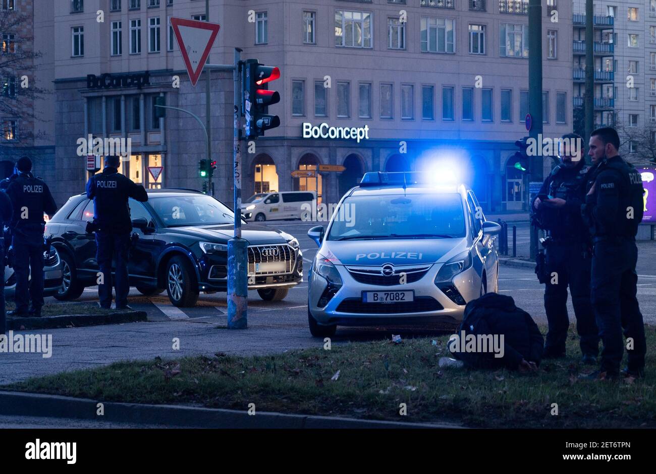 Berlin, Allemagne. 1er mars 2021. Lors d'une opération de police à Strausberger Platz, un menotté est assis sur le bord de l'herbe tandis qu'une voiture est garée dans la circulation venant en sens inverse. Credit: Christophe bateau/dpa - ATTENTION: (Les plaques d'immatriculation ont été pixélisées pour des raisons de confidentialité)/dpa/Alay Live News Banque D'Images