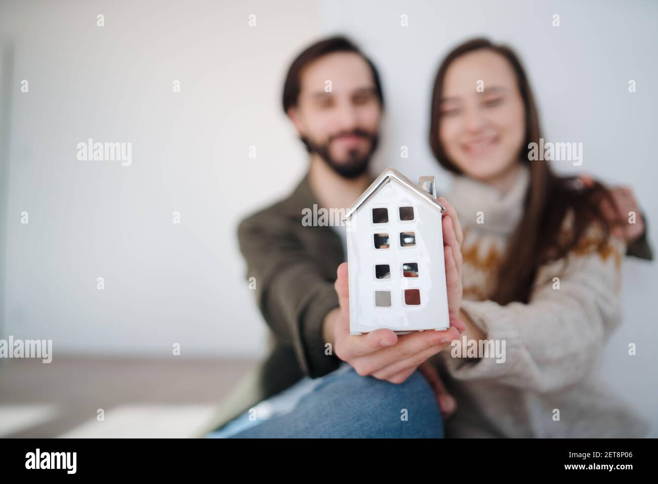 Jeunes propriétaires de couple tenant modèle de maison, déménagement, nouveau concept de maison et de relocalisation. Banque D'Images