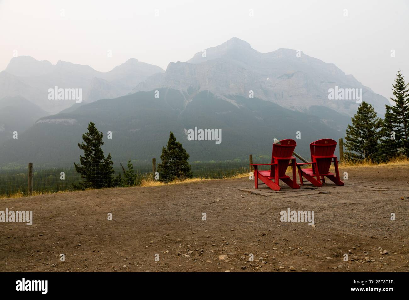 Chaises rouges Adirondack dans le parc national Banff, Canada avec des montagnes nuageux en arrière-plan. Banque D'Images