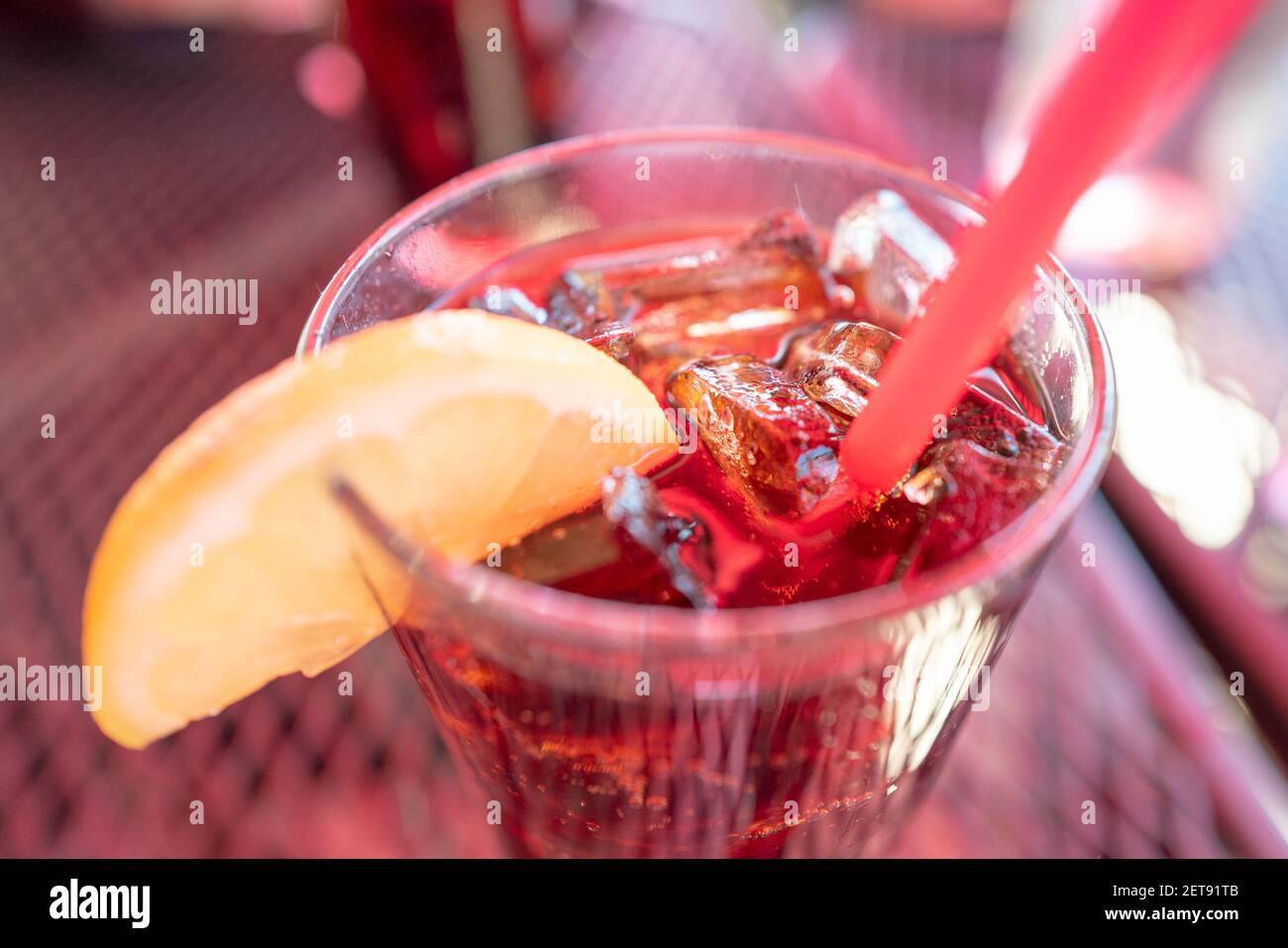 Gros plan d'une boisson froide dans un verre rempli de glace, avec un citron sur le rebord et une paille en plastique rouge, 17 février 2021. () Banque D'Images