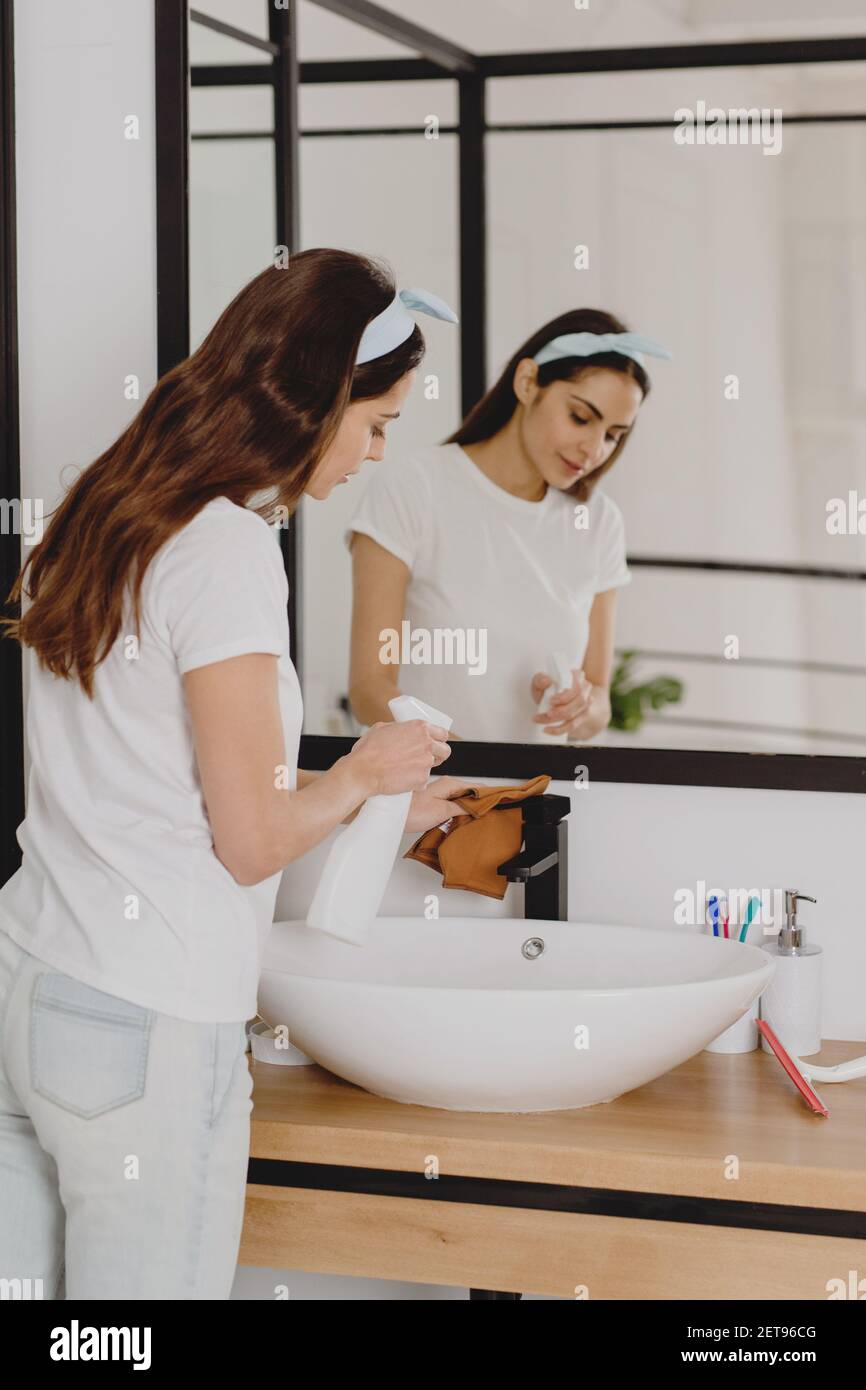 Belle femme nettoyant lavabo de salle de bains. Concept de nettoyage de ressort. Banque D'Images