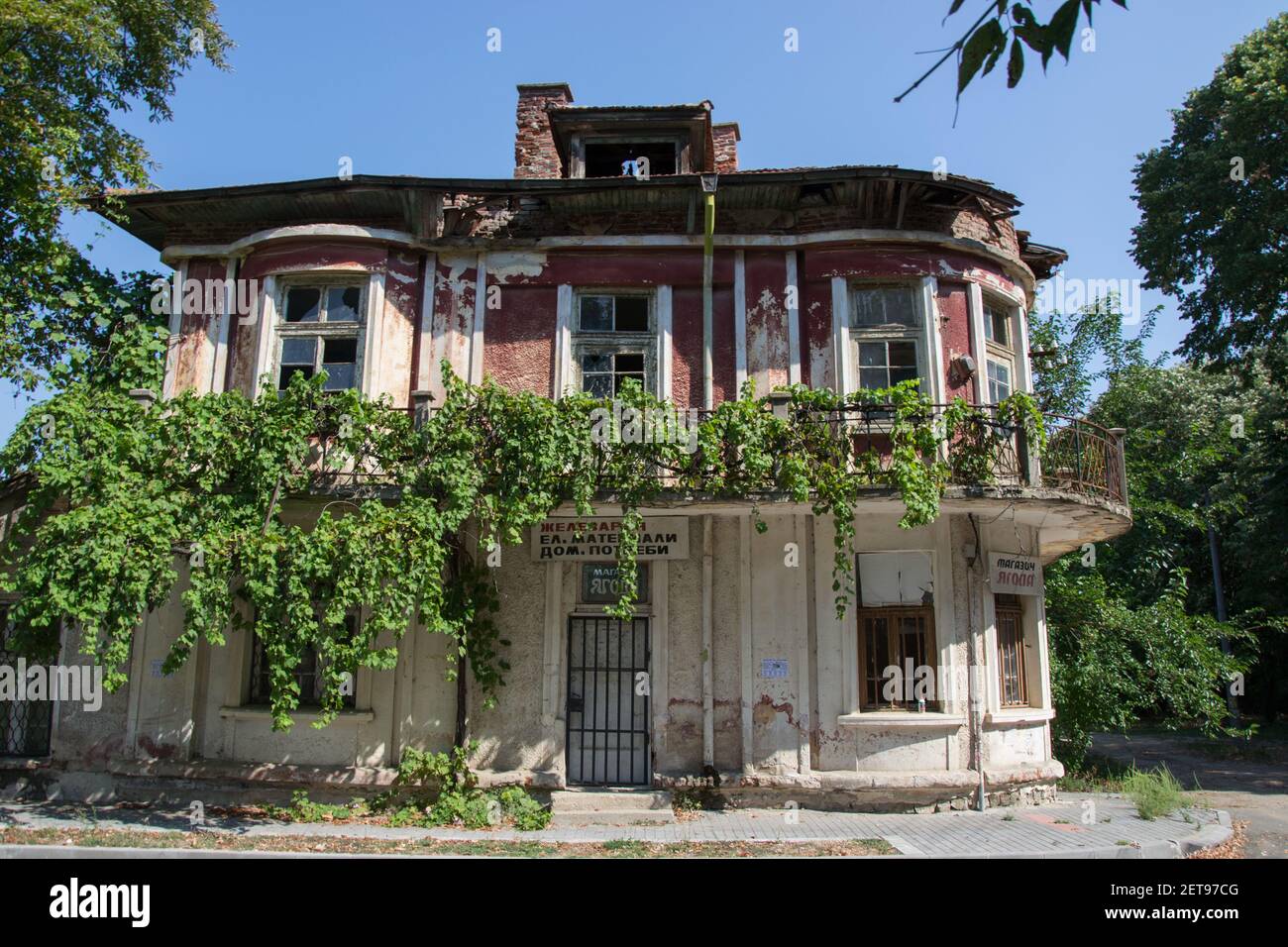 8 août 2020, selo Qgoda, Bulgarie - maison de village abandonnée couverte de plantes vertes, fenêtre cassée, dommages sur une ancienne maison sur la rue Banque D'Images
