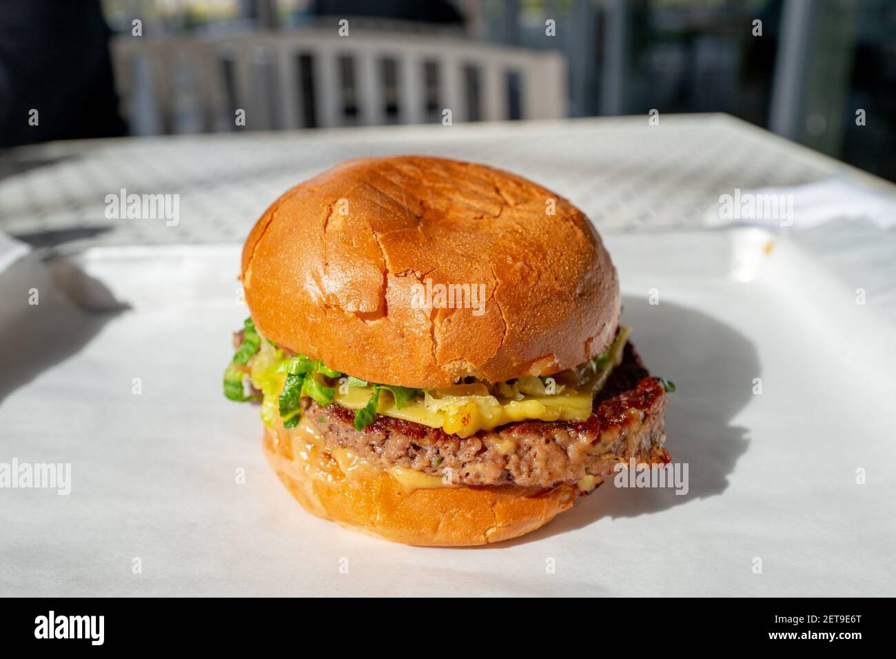 Gros plan en grand angle d'un cheeseburger, avec de la laitue et un petit pain, posé sur un plateau blanc, 18 février 2021. () Banque D'Images
