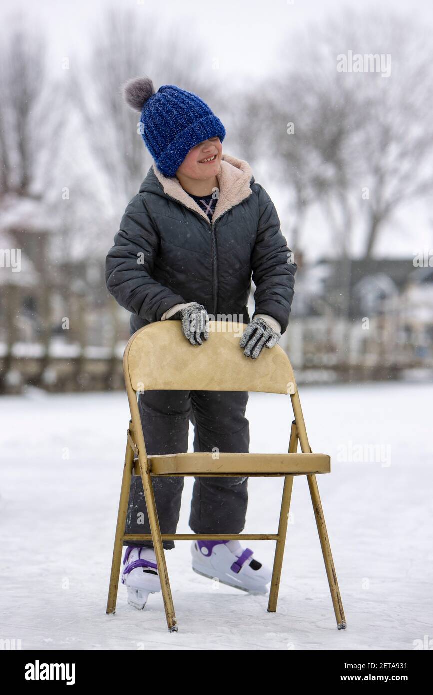 Fille apprenant à patiner sur glace tout en tenant sur une chaise Photo  Stock - Alamy