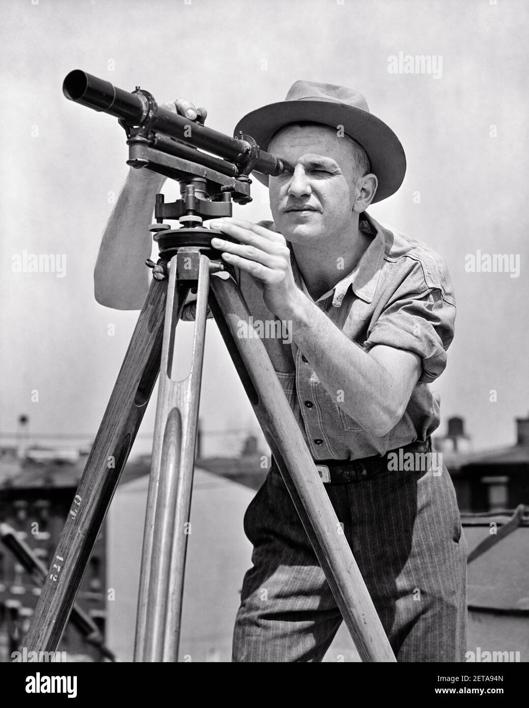 40S HOMME SUPERVISEUR DE CONSTRUCTION UTILISANT UNE THÉODOLITE DE NIVEAU SURVEYOR ON UN TRÉPIED - I34 HAR001 HARS SUPERVISEUR EMPLOIS UTILISANT SURVEYOR SURVEILLANT LA PRÉCISION DE LA POSITION DE L'HOMME MOYEN-ADULTE AU NIVEAU DE L'EMPLOYÉ THÉODOLITE NOIR ET BLANC DE RACE BLANCHE HAR001 LABOURING OLD FASHIONED Banque D'Images