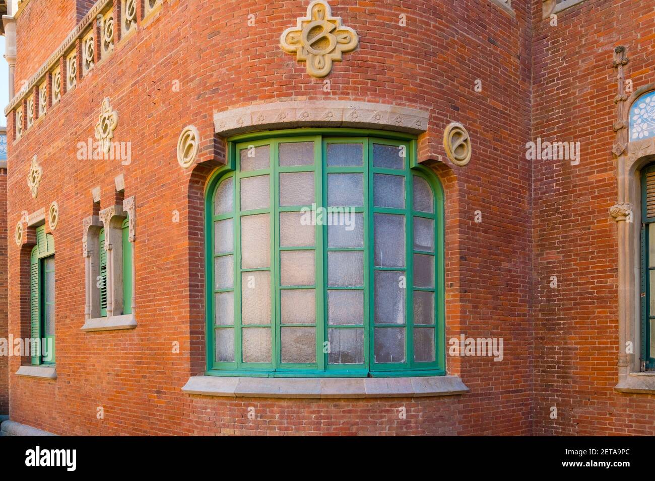 Fenêtre incurvée avec bordure verte dans un bâtiment de quartier en brique. À l'hôpital de la Santa Creu i Sant Pau à Barcelone, Espagne. Banque D'Images