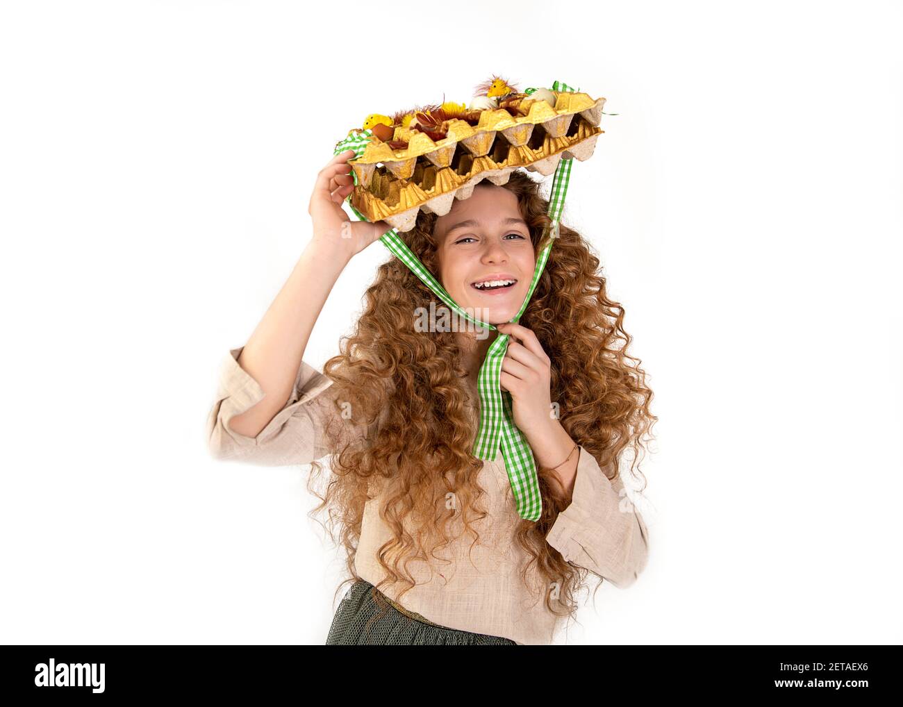 Créativité belle adolescente avec cheveux rouge bouclés mettre panier de  carton avec des décorations de Pâques oeufs comme chapeau sur la tête,  gaiement en studio sur le dos blanc Photo Stock -