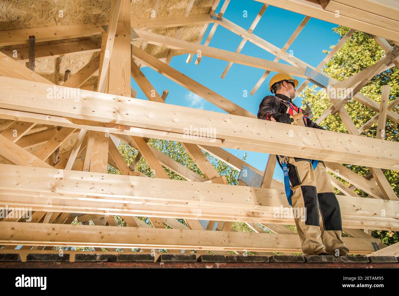 Squelette en bois de l'édifice de la maison. Travailleur d'entrepreneur caucasien sur le cadre Attic. Thème industriel. Banque D'Images