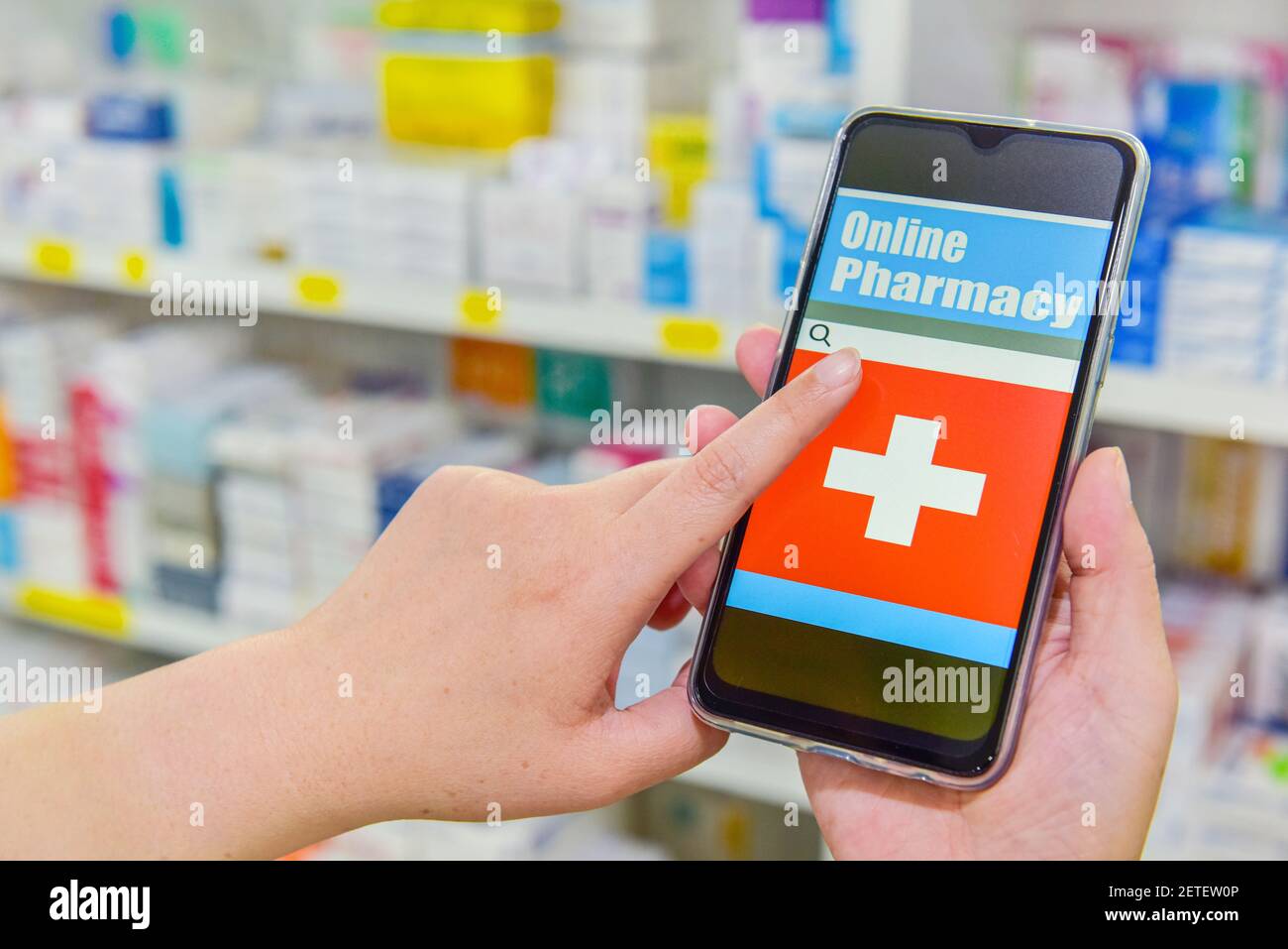 Pharmacien utilisant un téléphone intelligent mobile pour la barre de recherche sur l'affichage dans les étagères de pharmacie arrière-plan. Concept médical en ligne Banque D'Images