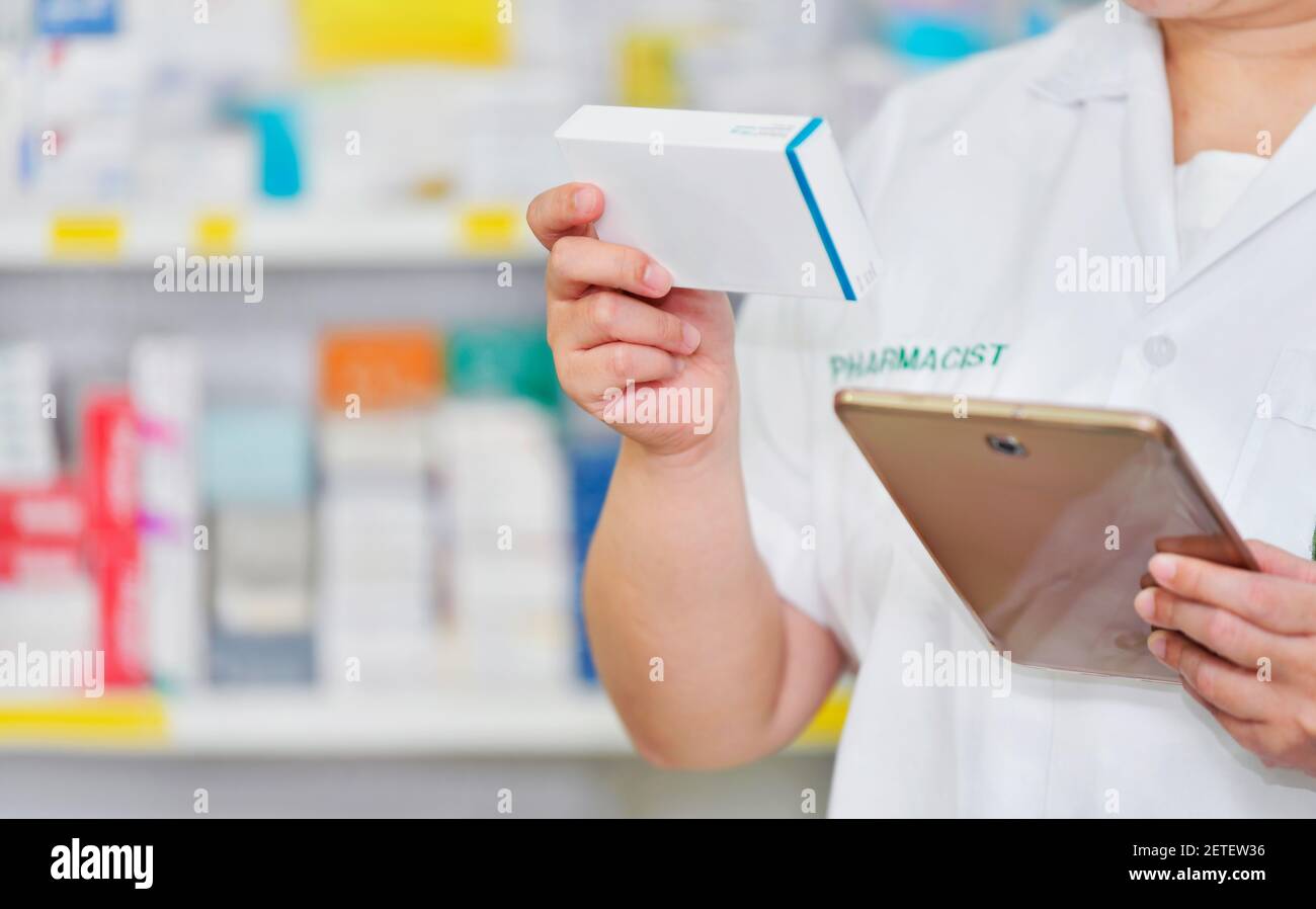 Pharmacien utilisant une tablette pour ordinateur pour la barre de recherche sur l'affichage dans les étagères de pharmacie arrière-plan. Concept médical en ligne Banque D'Images
