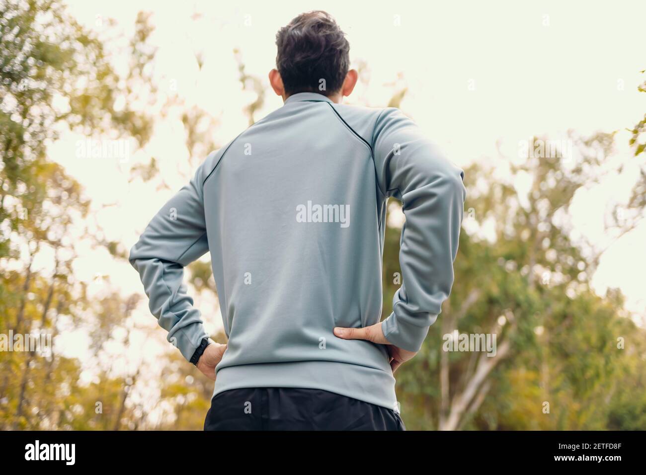 Un homme avec les mains à la taille et voir dans le ciel en veste après la course. Banque D'Images