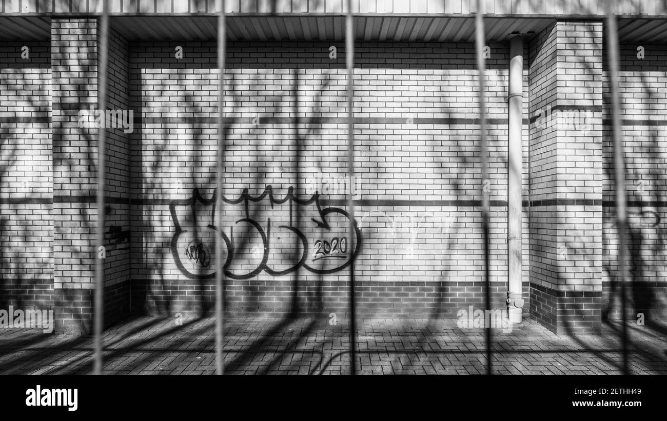 Graffitis sur un bâtiment abandonné pris par une clôture rouillée. Banque D'Images