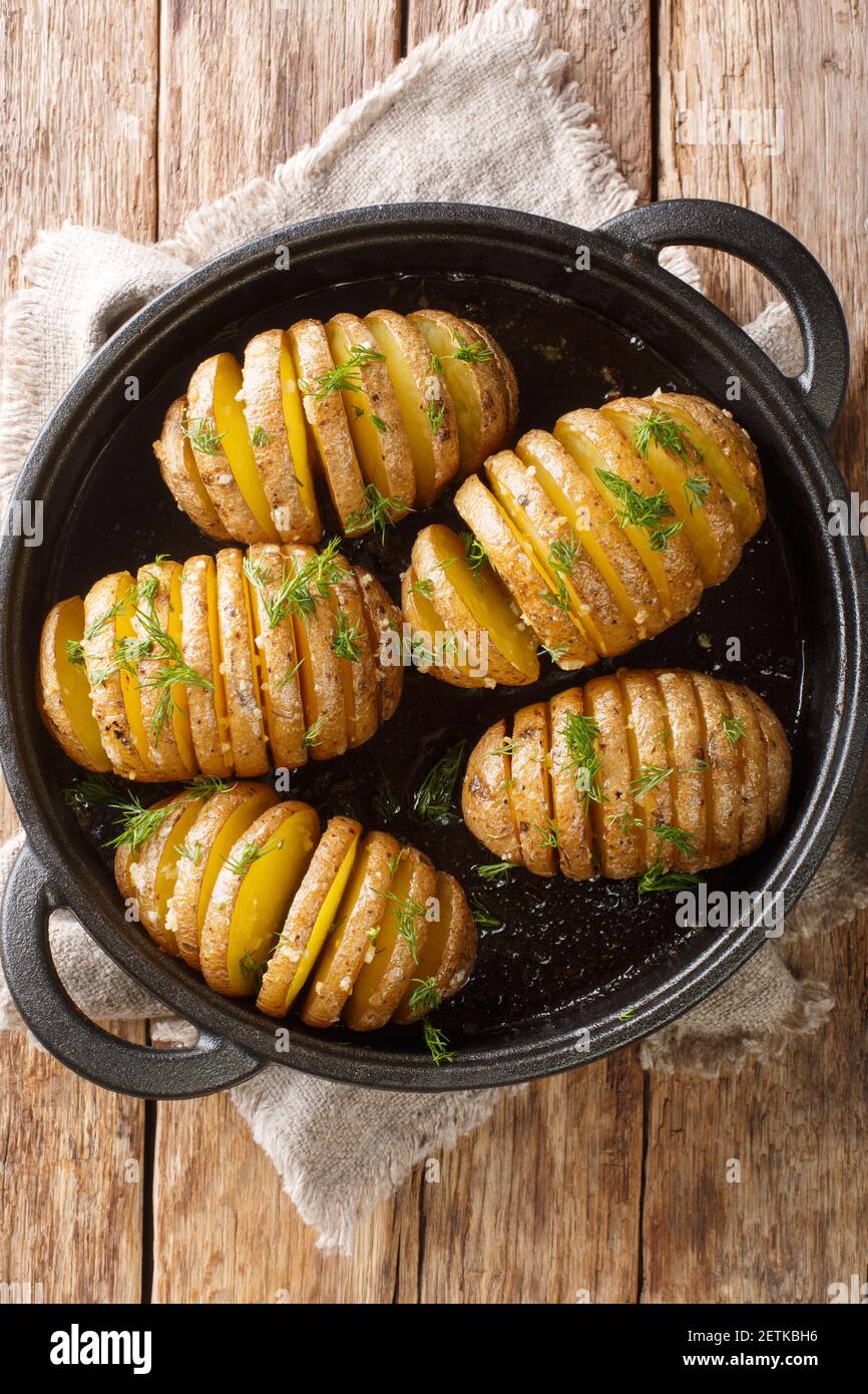 Les pommes de terre Hasselback sont des pommes de terre finement tranchées qui sont cuites à la perfection dans un brun doré avec du beurre et de l'ail dans une casserole sur la table. Vertica Banque D'Images