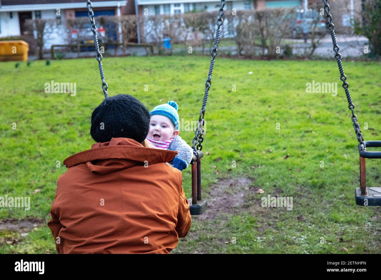 Bébé caucasien sur l'oscillation avec la mère en hiver. Banque D'Images